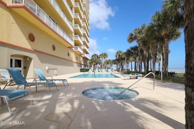 view of pool with a hot tub and a patio