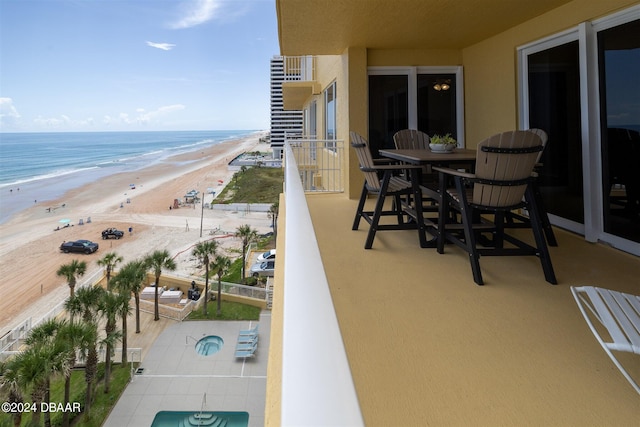 balcony with a view of the beach, a water view, and a patio area