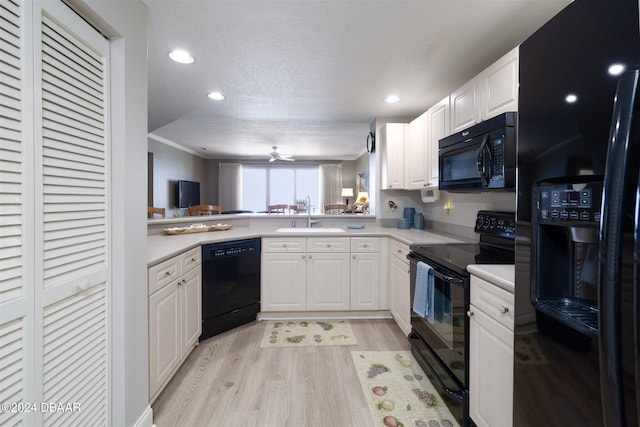 kitchen with kitchen peninsula, black appliances, a textured ceiling, sink, and white cabinetry