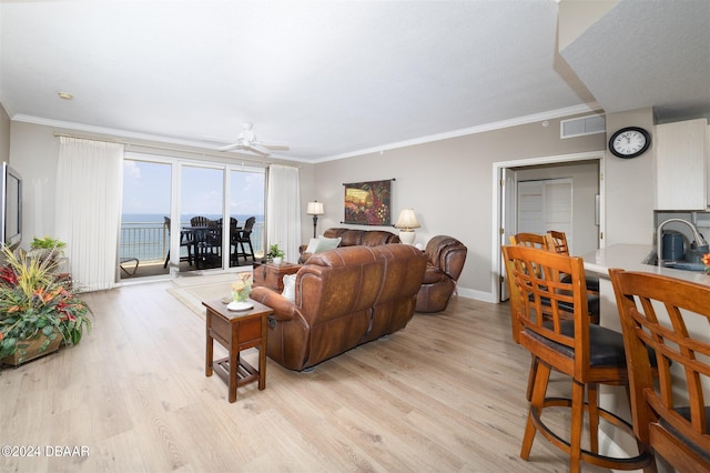 living room featuring ornamental molding, light wood-type flooring, a water view, and ceiling fan