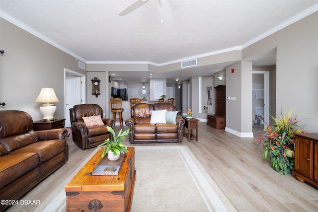 living room featuring light hardwood / wood-style floors, ceiling fan, a textured ceiling, and ornamental molding