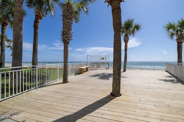 wooden terrace featuring a water view and a view of the beach