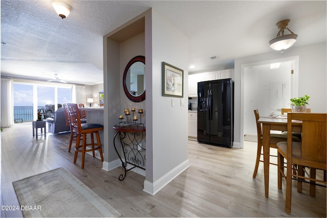 hallway with a water view, a textured ceiling, and light wood-type flooring