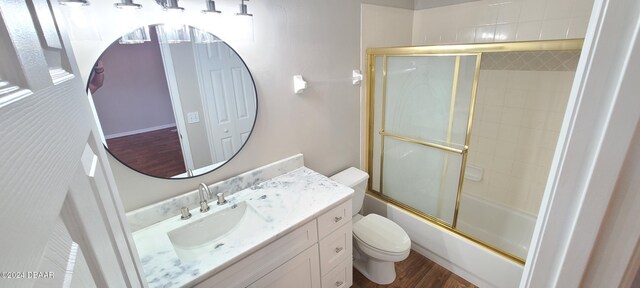 full bathroom featuring hardwood / wood-style floors, vanity, toilet, and shower / bath combination with glass door