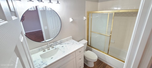 full bathroom with bath / shower combo with glass door, vanity, hardwood / wood-style flooring, and toilet