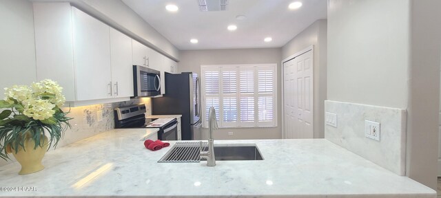 kitchen with white cabinets, kitchen peninsula, appliances with stainless steel finishes, and sink