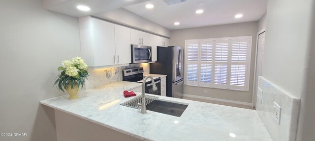 kitchen with white cabinetry, sink, appliances with stainless steel finishes, tasteful backsplash, and light stone countertops