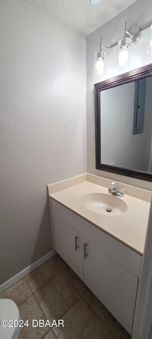 bathroom featuring electric panel, vanity, a textured ceiling, tile patterned flooring, and toilet