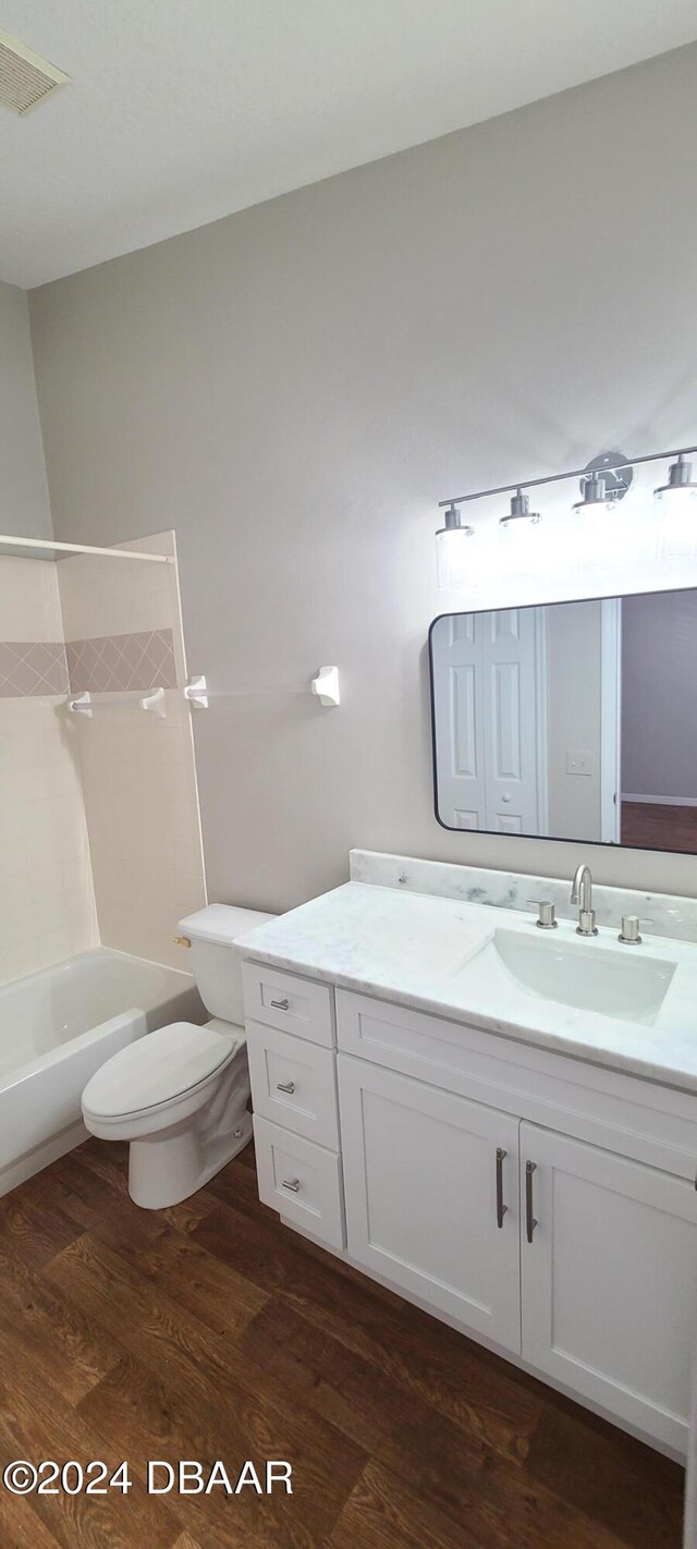 full bathroom with hardwood / wood-style floors, vanity, toilet, and shower / washtub combination