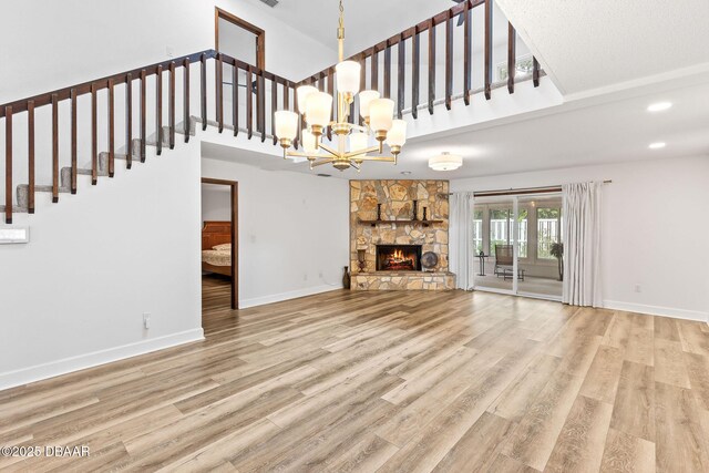 12 Big Buck Trl, Ormond Beach, FL 32174 - unfurnished living room with a chandelier, wood finished floors, a towering ceiling, a stone fireplace, and recessed lighting