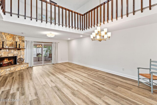 12 Big Buck Trl, Ormond Beach, FL 32174 - unfurnished living room with a towering ceiling, wood finished floors, a stone fireplace, a chandelier, and recessed lighting