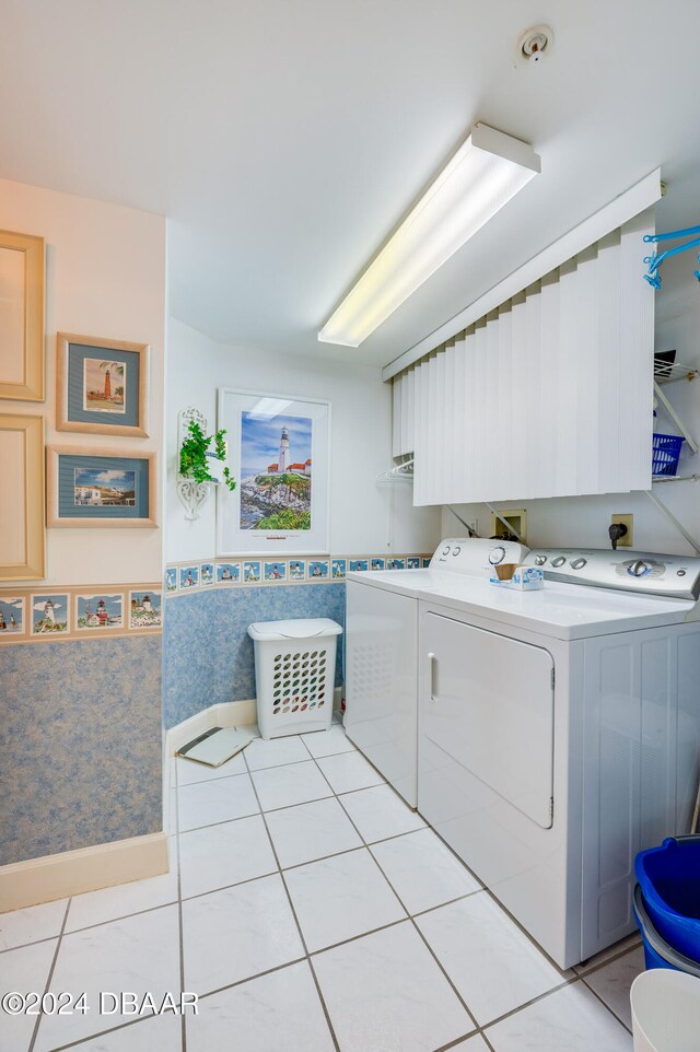 clothes washing area with light tile patterned floors and washer and clothes dryer