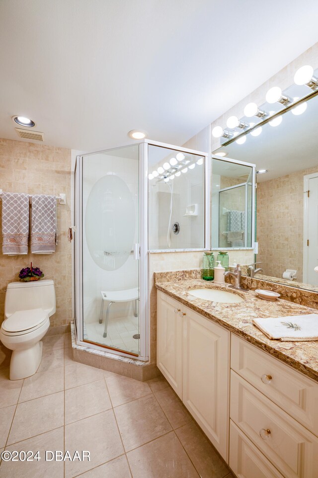 bathroom featuring tile patterned flooring, vanity, an enclosed shower, toilet, and tile walls