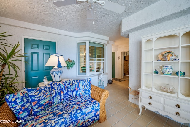 living room with a textured ceiling, light tile patterned floors, and ceiling fan