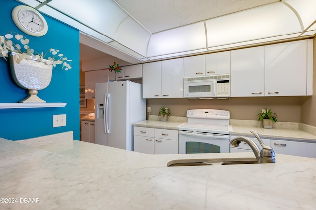 kitchen featuring white cabinets, white appliances, sink, and light stone counters