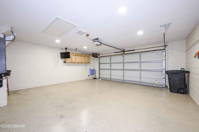 garage featuring concrete block wall and a garage door opener
