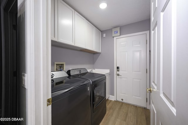 laundry area featuring cabinet space, washer and clothes dryer, and light wood-style flooring