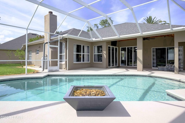 outdoor pool featuring a ceiling fan, glass enclosure, a fire pit, and a patio area