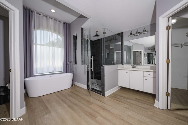 bathroom with vanity, a freestanding tub, baseboards, wood finished floors, and a stall shower