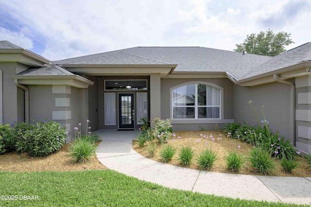 doorway to property featuring a shingled roof and stucco siding