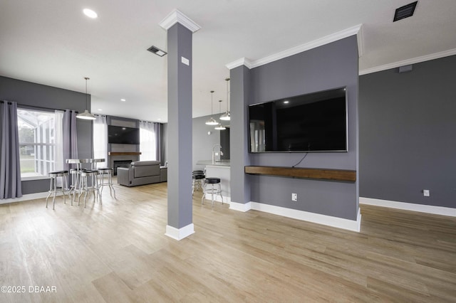 living room with visible vents, crown molding, a fireplace, wood finished floors, and baseboards