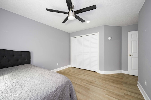 bedroom with a ceiling fan, baseboards, light wood finished floors, and a closet