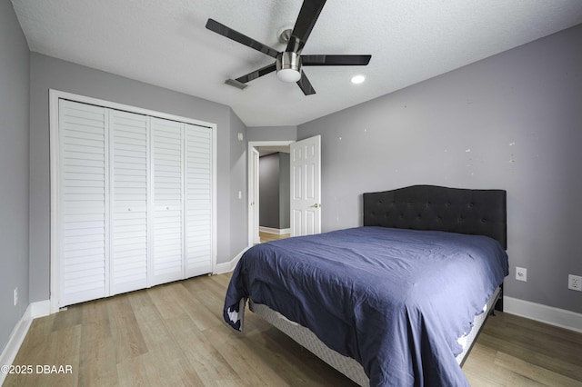 bedroom featuring a ceiling fan, baseboards, wood finished floors, visible vents, and a closet