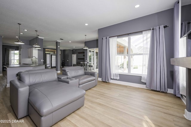 living room with recessed lighting, baseboards, and light wood-style flooring