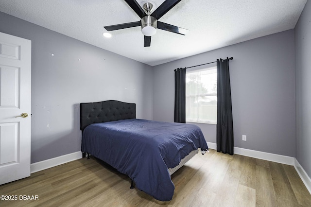 bedroom featuring a textured ceiling, baseboards, a ceiling fan, and wood finished floors