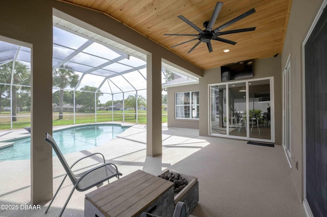pool featuring a ceiling fan, glass enclosure, and a patio area