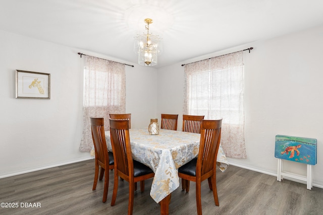 dining space with dark wood-type flooring and a notable chandelier