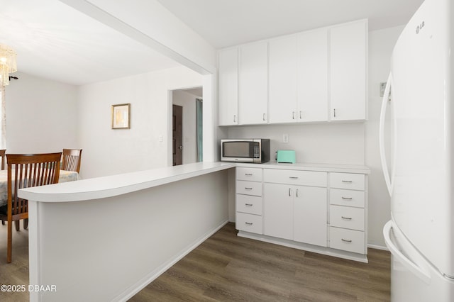 kitchen featuring white cabinetry, white fridge, dark hardwood / wood-style flooring, and kitchen peninsula