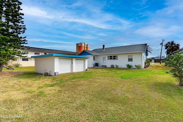 back of house with a garage and a lawn