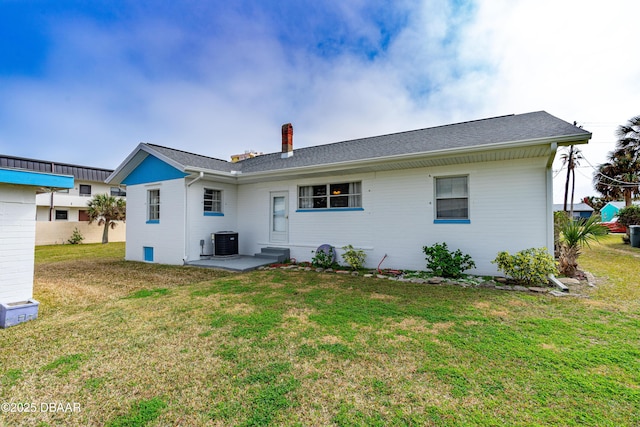 rear view of house with cooling unit and a lawn