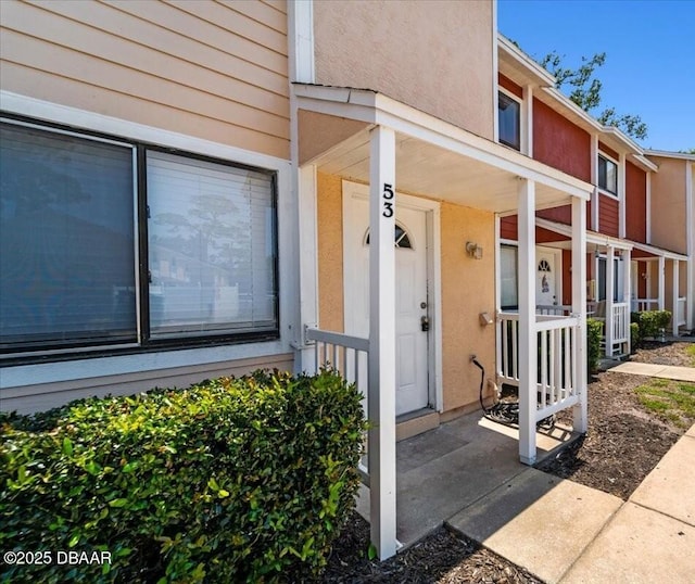 property entrance with a porch and stucco siding