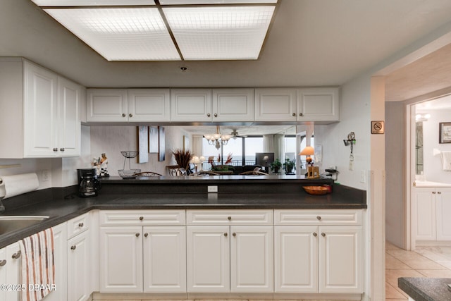 kitchen with an inviting chandelier, white cabinets, and dark countertops