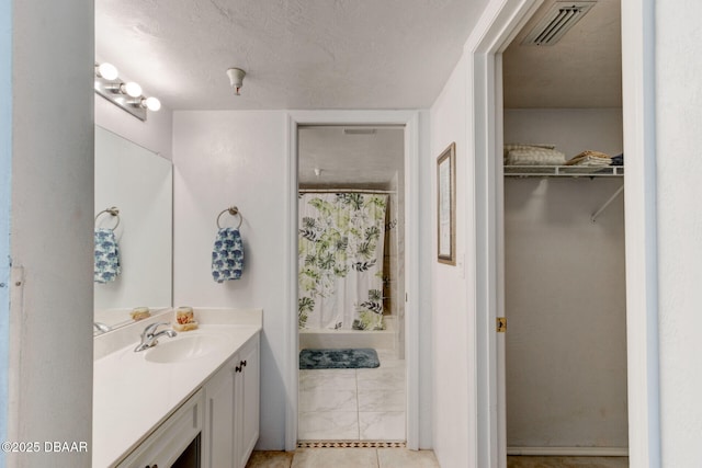 bathroom featuring a shower with curtain, a walk in closet, a textured ceiling, visible vents, and vanity