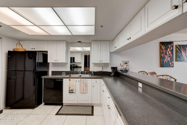 kitchen with white cabinets, dark countertops, a sink, light tile patterned floors, and black appliances