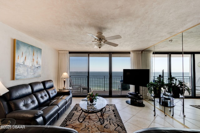 living room with light tile patterned floors, ceiling fan, expansive windows, and a wealth of natural light
