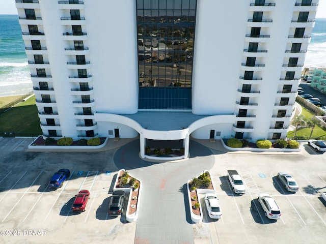 view of building exterior with a view of the beach, a water view, and uncovered parking