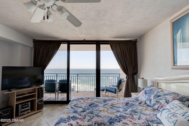 tiled bedroom with a ceiling fan, floor to ceiling windows, a water view, and access to exterior