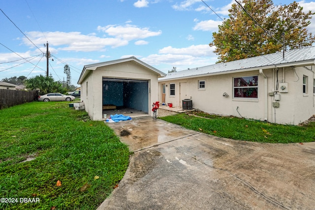 rear view of house with a garage, a lawn, and central AC