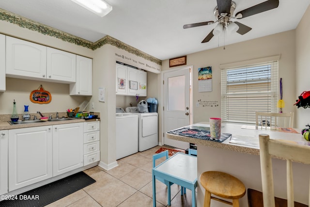 kitchen featuring light tile patterned floors, sink, a kitchen breakfast bar, white cabinets, and washing machine and dryer