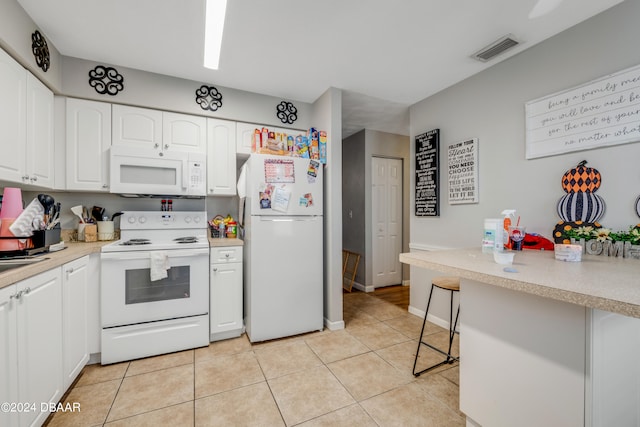 kitchen featuring white cabinetry, white appliances, light tile patterned floors, and a breakfast bar area