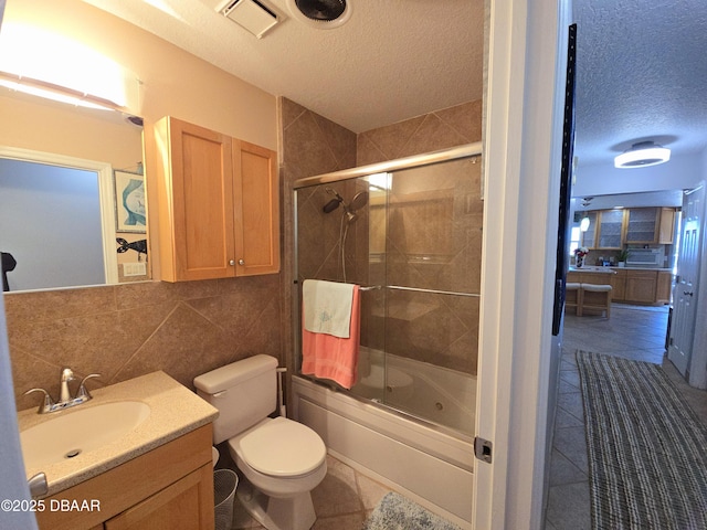 full bath with shower / bath combination with glass door, toilet, tile patterned floors, and a textured ceiling