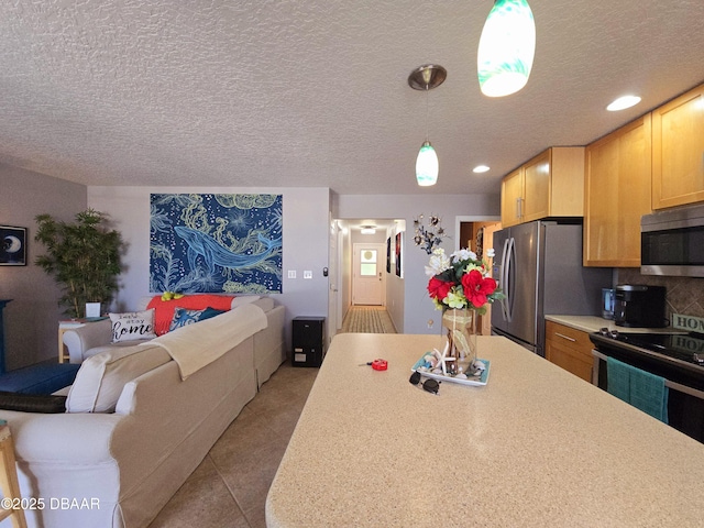 kitchen featuring tile patterned flooring, pendant lighting, open floor plan, light countertops, and appliances with stainless steel finishes