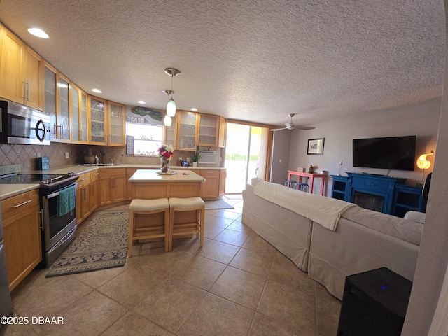 kitchen featuring decorative backsplash, a kitchen island, open floor plan, light countertops, and appliances with stainless steel finishes
