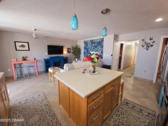 kitchen with a kitchen island, a ceiling fan, light countertops, light tile patterned floors, and open floor plan