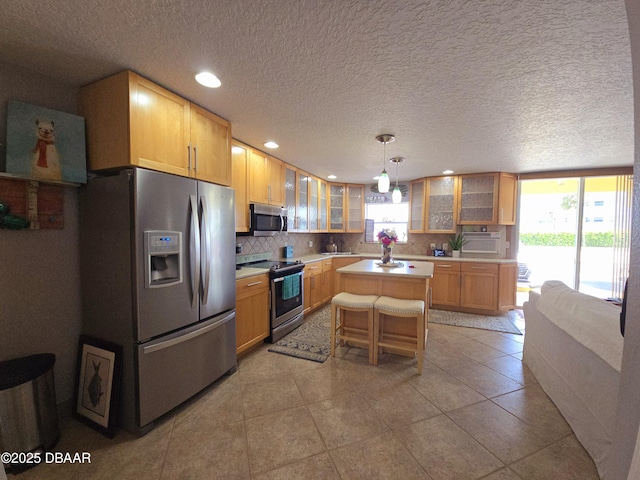 kitchen with glass insert cabinets, a center island, light countertops, tasteful backsplash, and stainless steel appliances