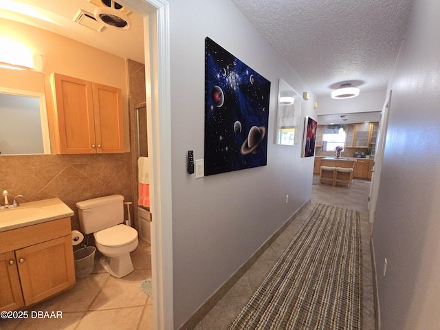 hall with tile patterned flooring, a sink, and a textured ceiling